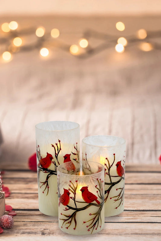 Decorative candles with cardinal designs on a wooden surface with festive decorations.