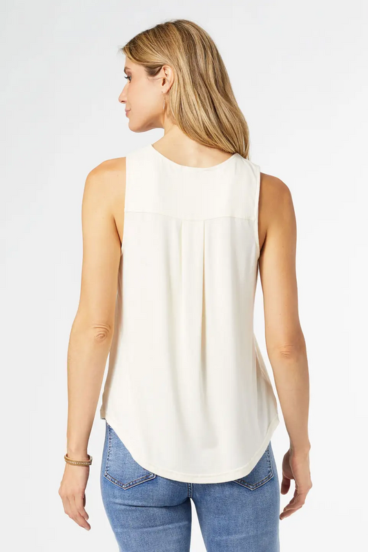 Woman wearing a white sleeveless top and blue jeans on a plain background