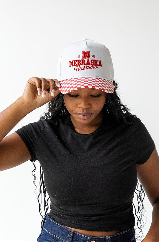 Person wearing a black crop top, blue jeans, and a white cap with red text on a white background