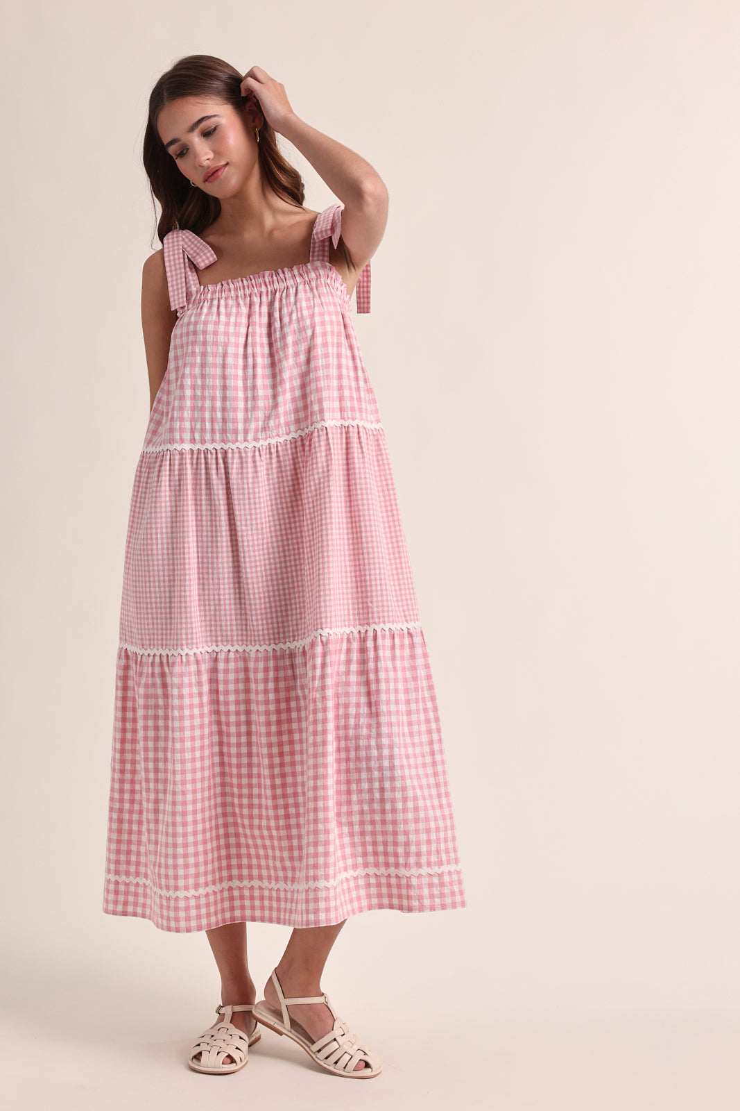 Woman wearing a pink checkered dress against a beige background