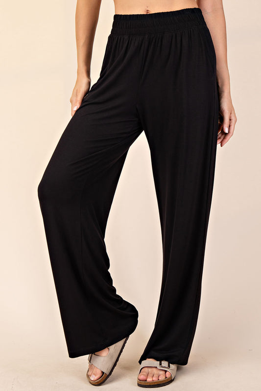 Black wide-leg pants worn by a person on a beige background