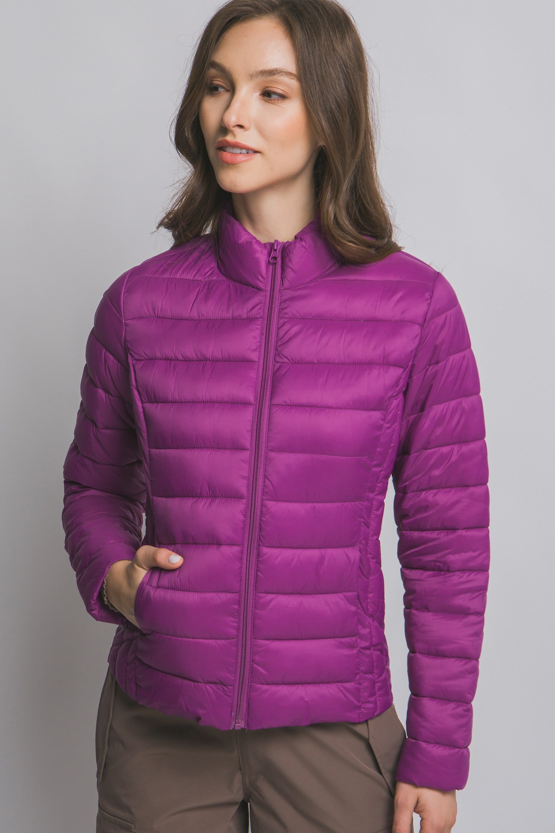 Woman wearing a purple puffer jacket on a gray background
