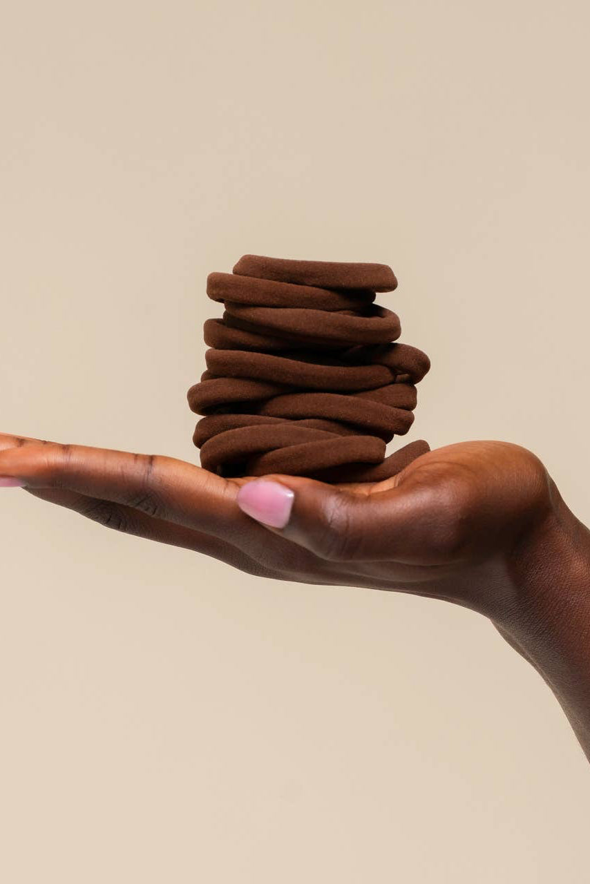 Hand holding a stack of brown cookies against a beige background