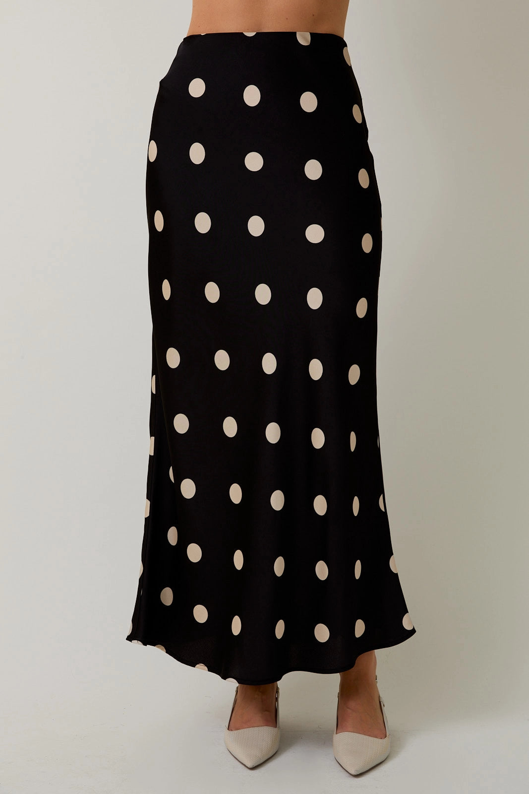 Black polka dot skirt worn by a person on a plain background