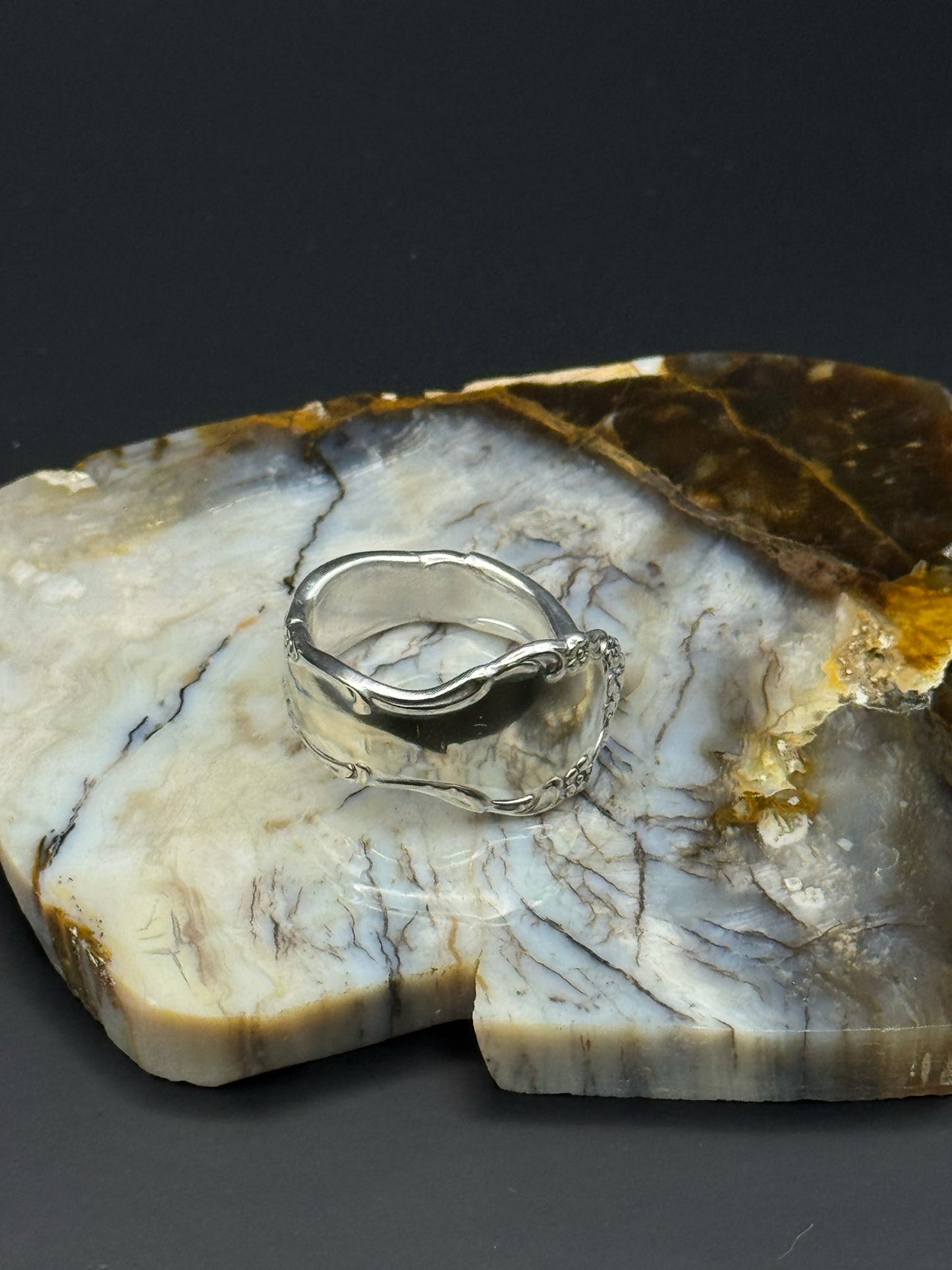 Silver ring on a piece of polished stone with a dark background