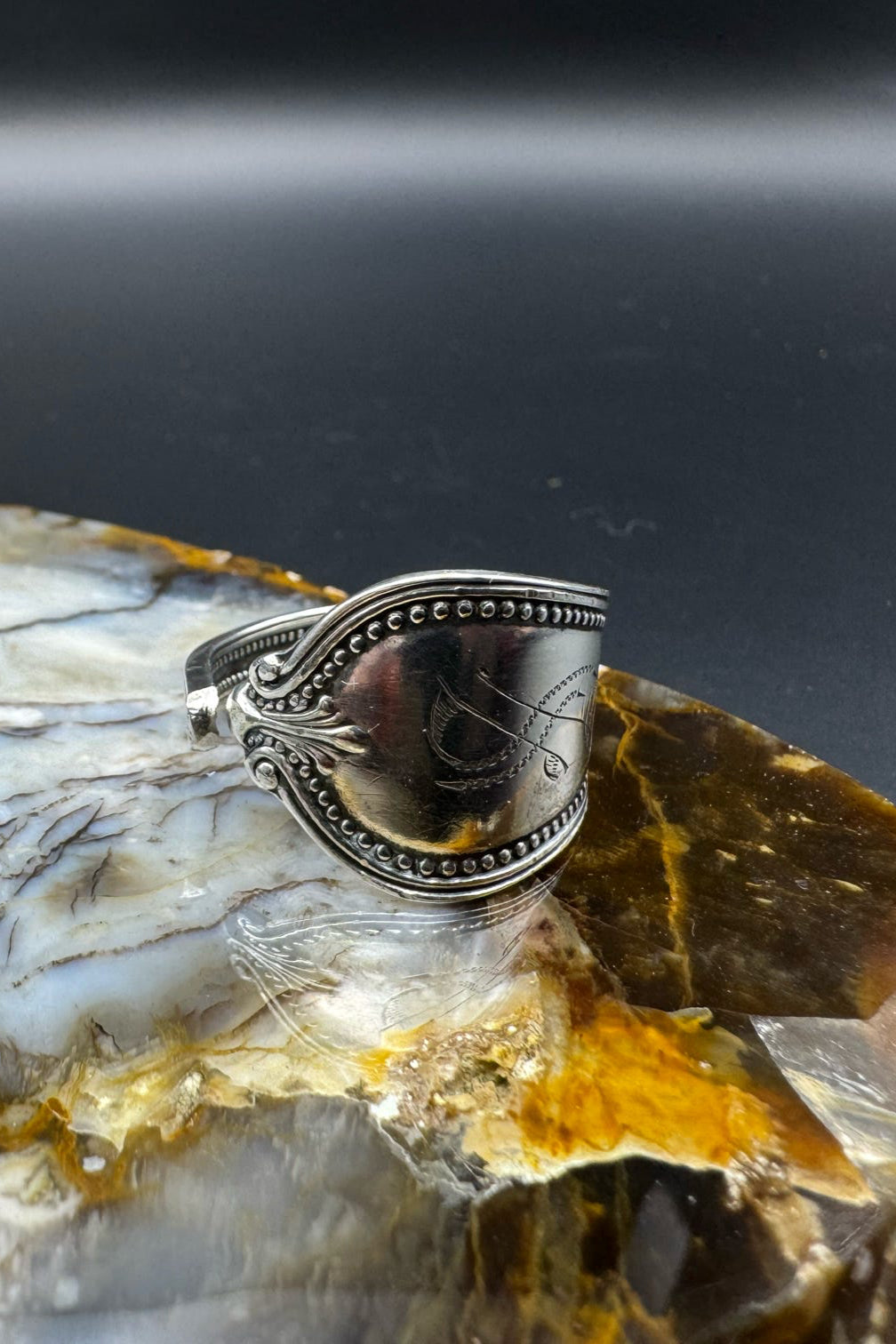 Silver ring with intricate design on a piece of polished stone