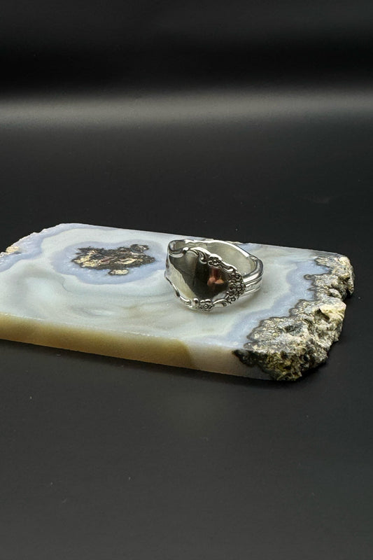 Silver ring on a piece of agate stone with a dark background