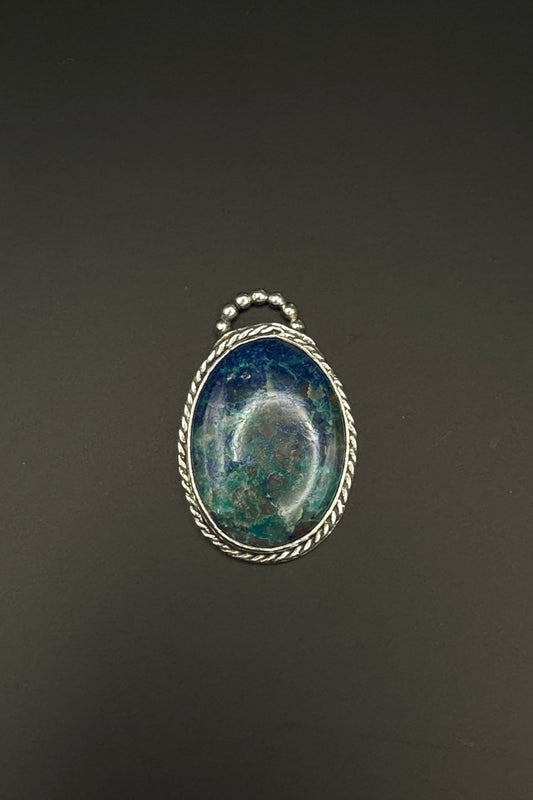 Pendant with blue stone and silver wire wrapping on a dark background
