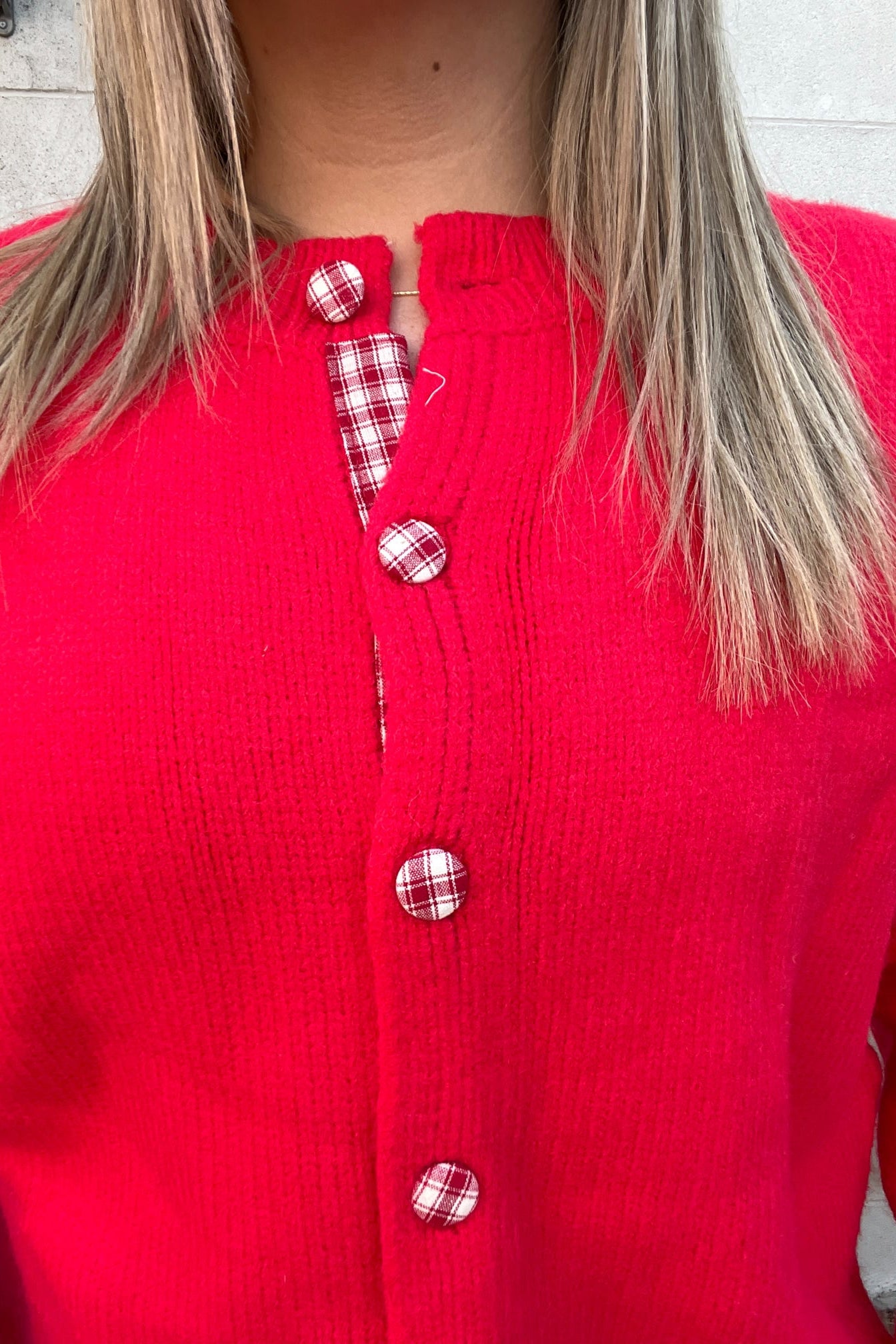 Red button-up shirt with plaid patterns worn by a person, blurred background