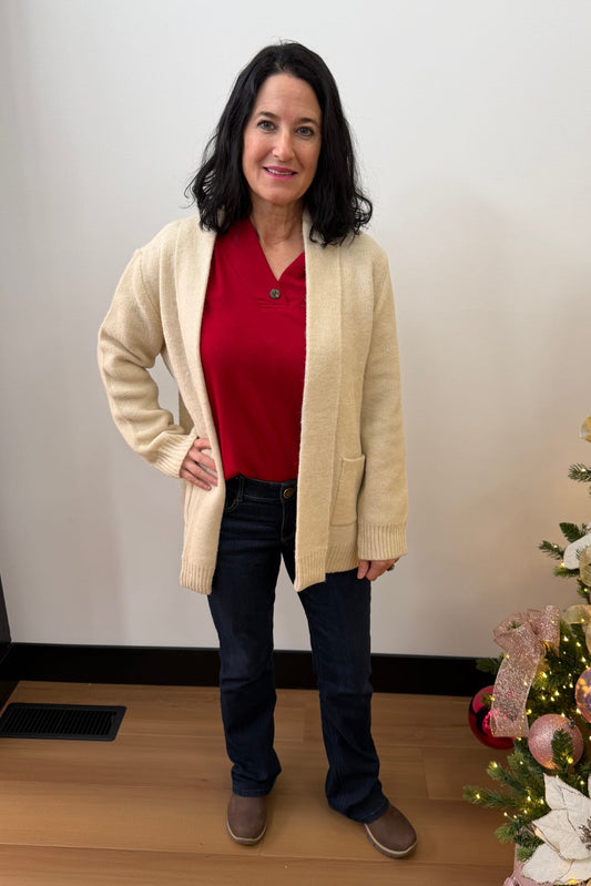 Woman standing next to a decorated Christmas tree indoors.
