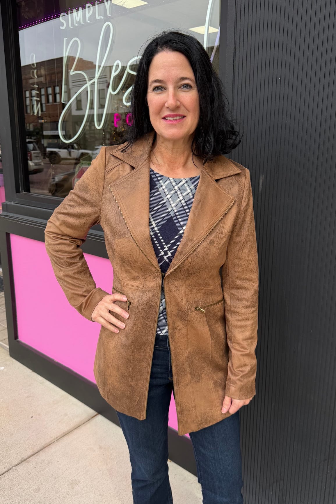 Woman wearing a brown coat standing in front of a store with a pink and black exterior.