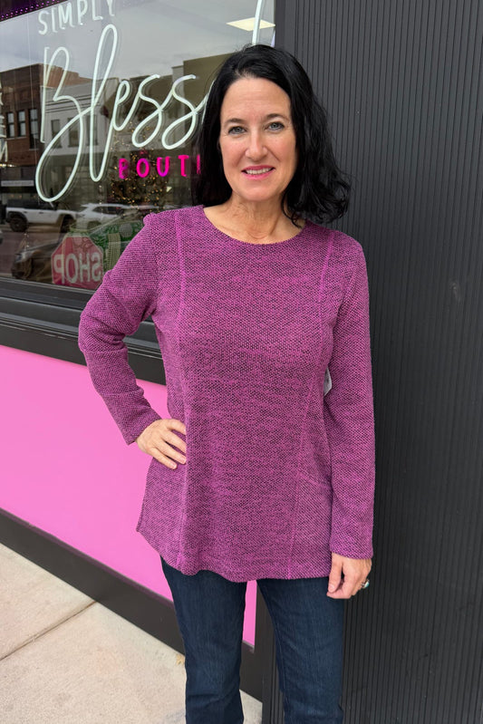 Woman in a purple sweater standing in front of a store with a pink and black exterior.