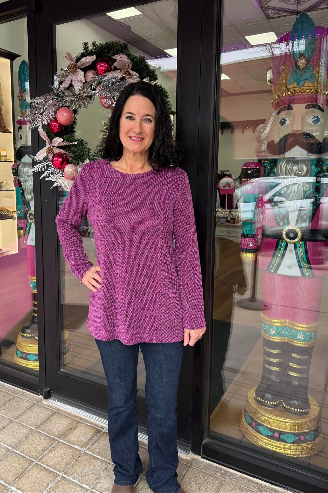 Woman in a purple sweater standing in front of a store entrance with decorative nutcrackers.