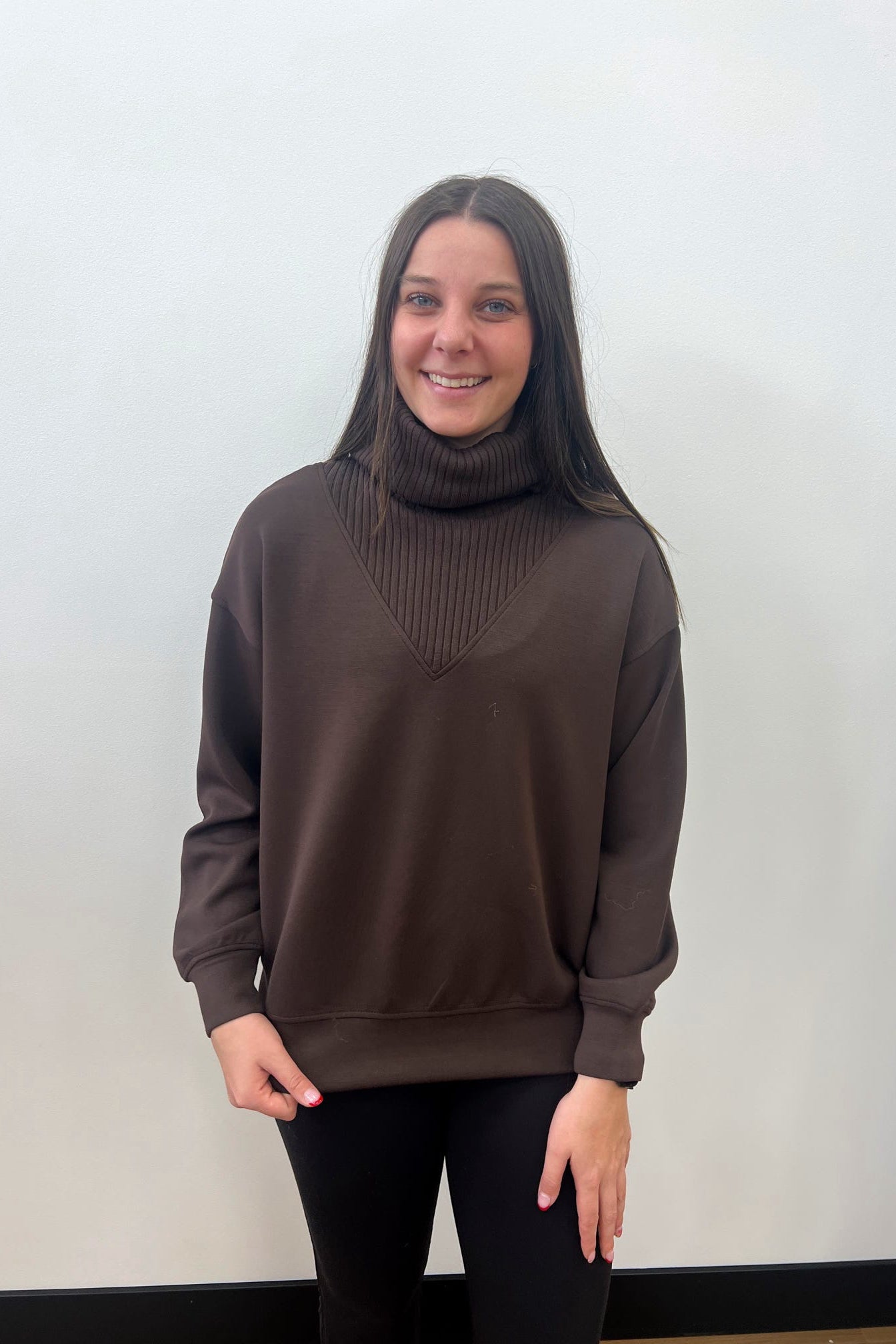 Person wearing a brown sweater against a plain background