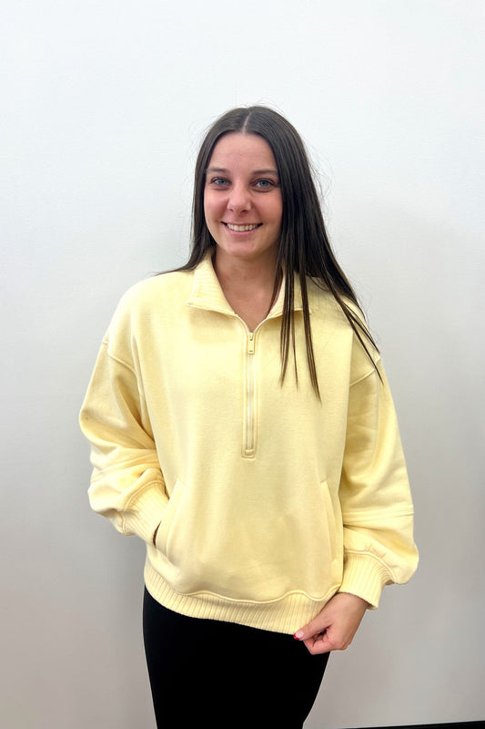 Person wearing a yellow sweater against a plain background