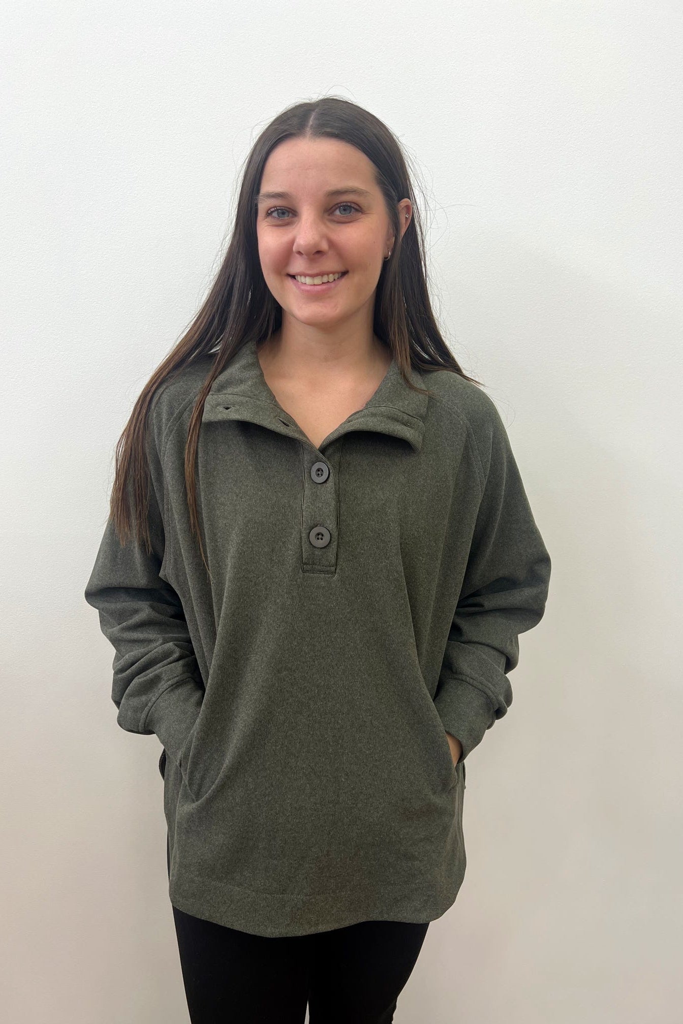 Woman wearing a green pullover with buttons against a white background