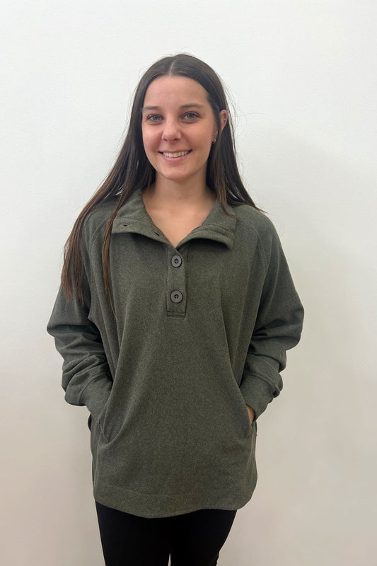 Woman wearing a green pullover with buttons against a white background