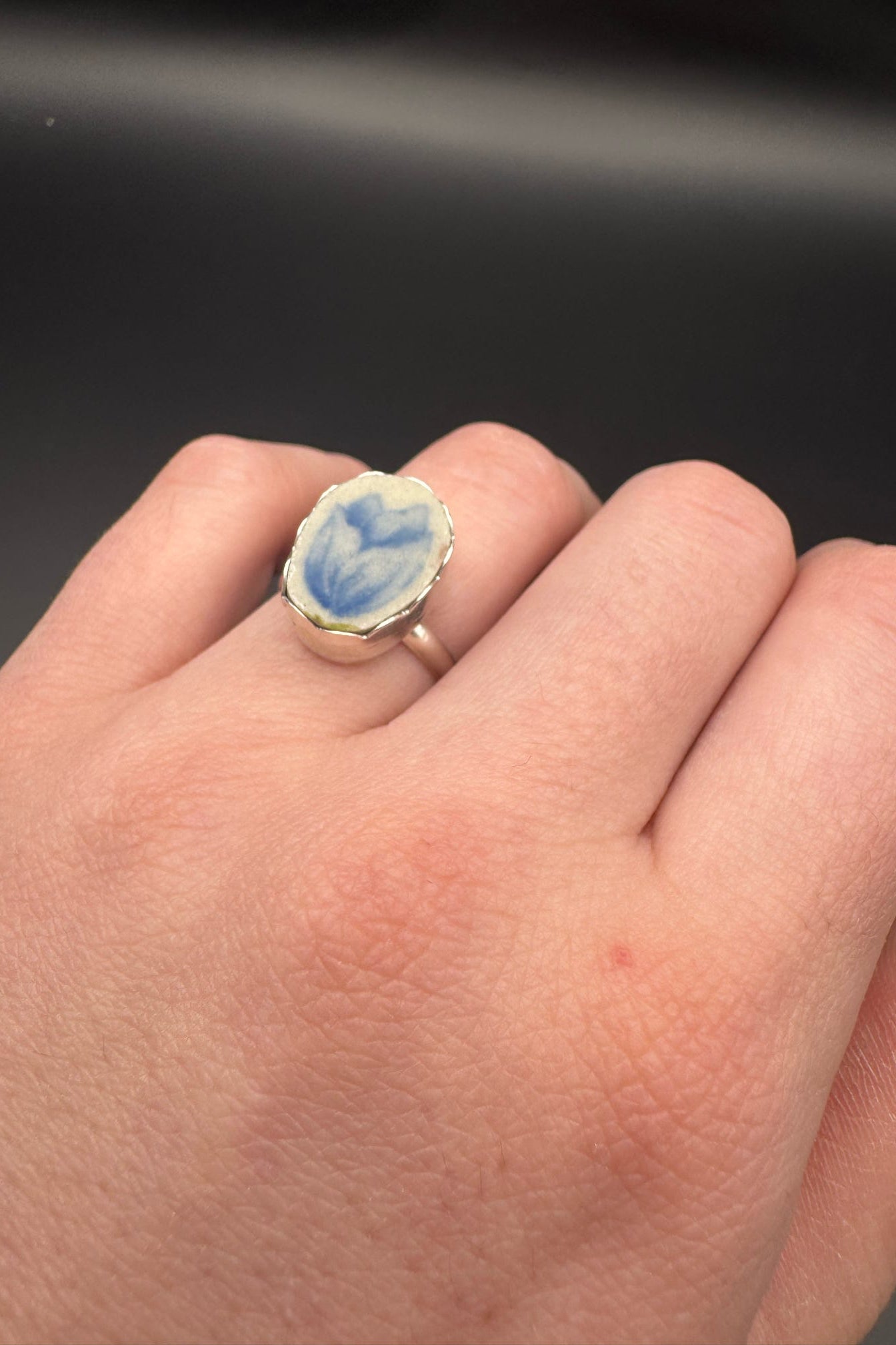 Blue tulip design on ring set in sterling silver; displayed on hand