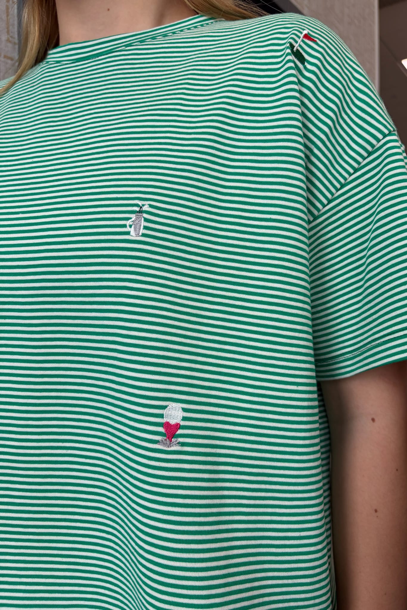 Green and white striped shirt with small embroidered designs on a person wearing it.