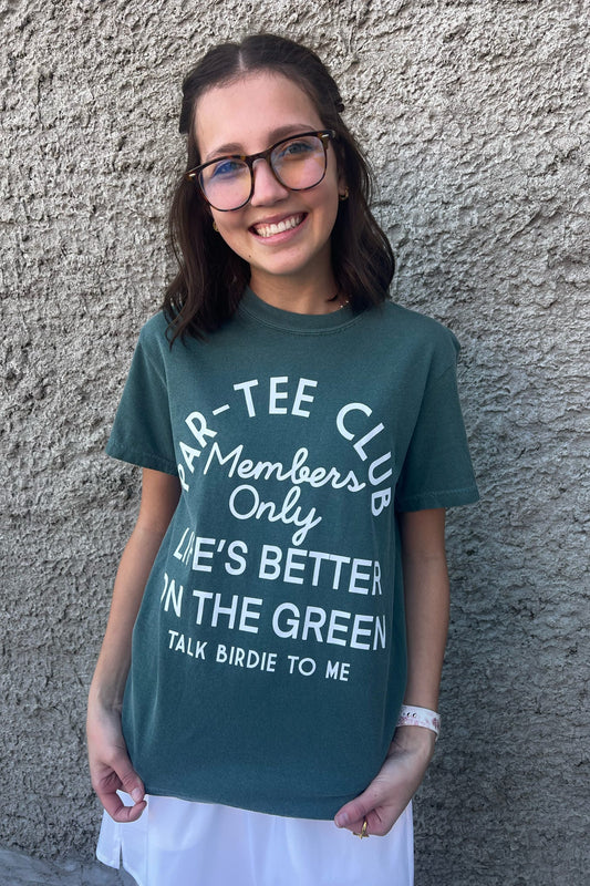 Person wearing a teal t-shirt with white text against a gray wall