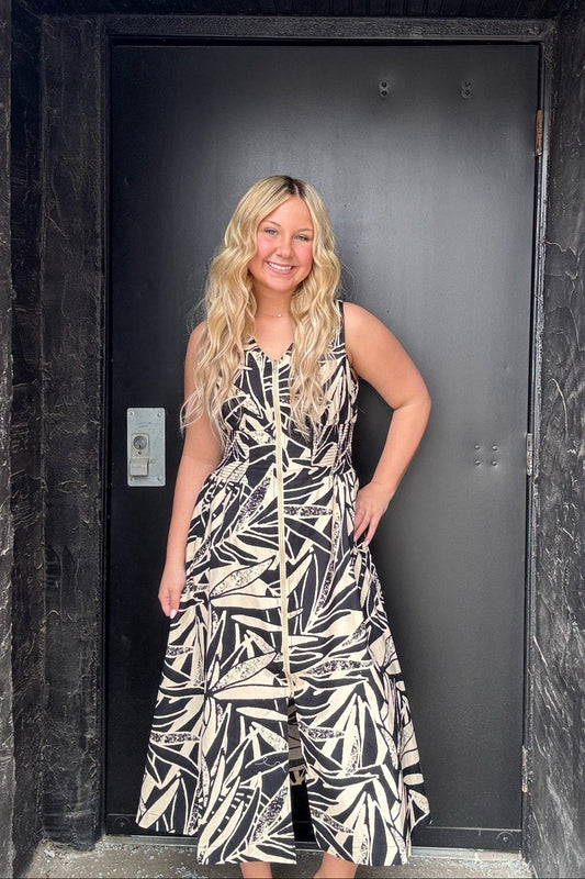 Woman in a patterned dress standing in front of a black door.
