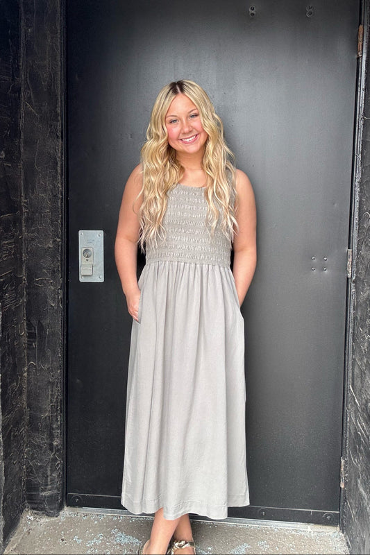 Woman in a gray dress standing in front of a black door.