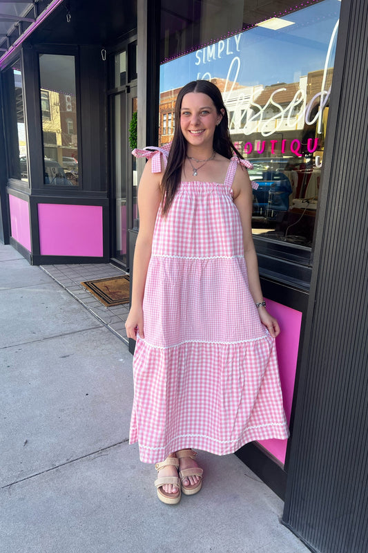 Woman in a pink checkered dress standing outside a store with a pink interior.