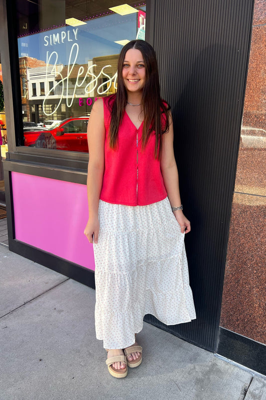 Woman in a red top and white skirt standing outside a building with a pink and black exterior.