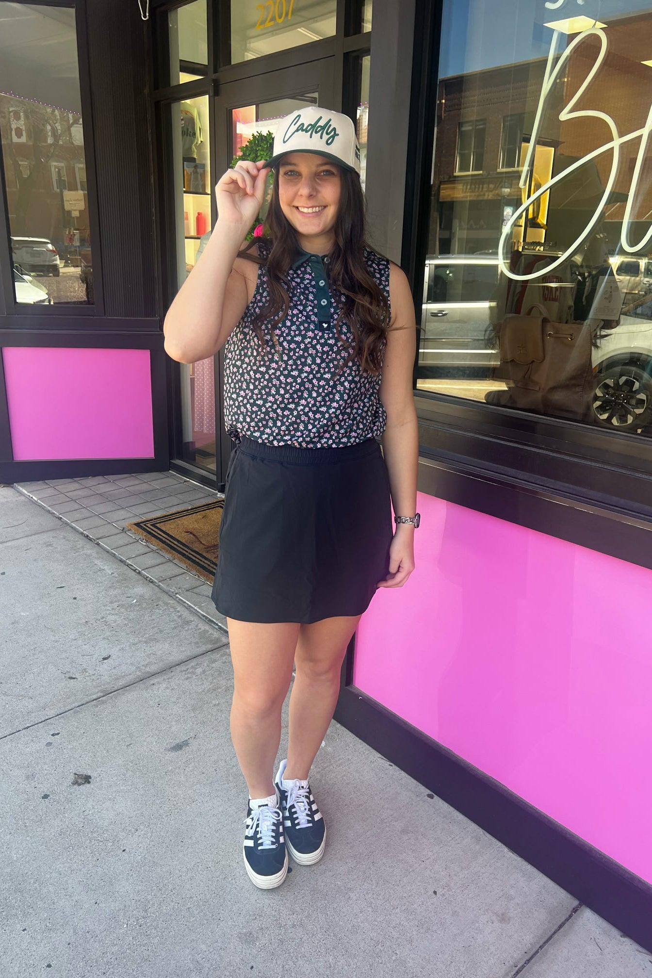 Woman holding a hat in front of a pink building