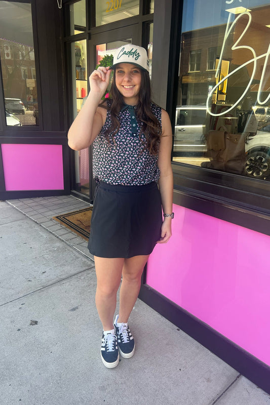 Woman holding a hat in front of a pink building