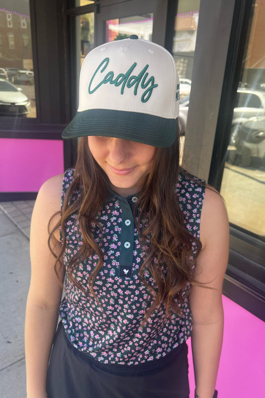 Person wearing a cap with 'Caddy' text, standing outdoors near a building entrance.