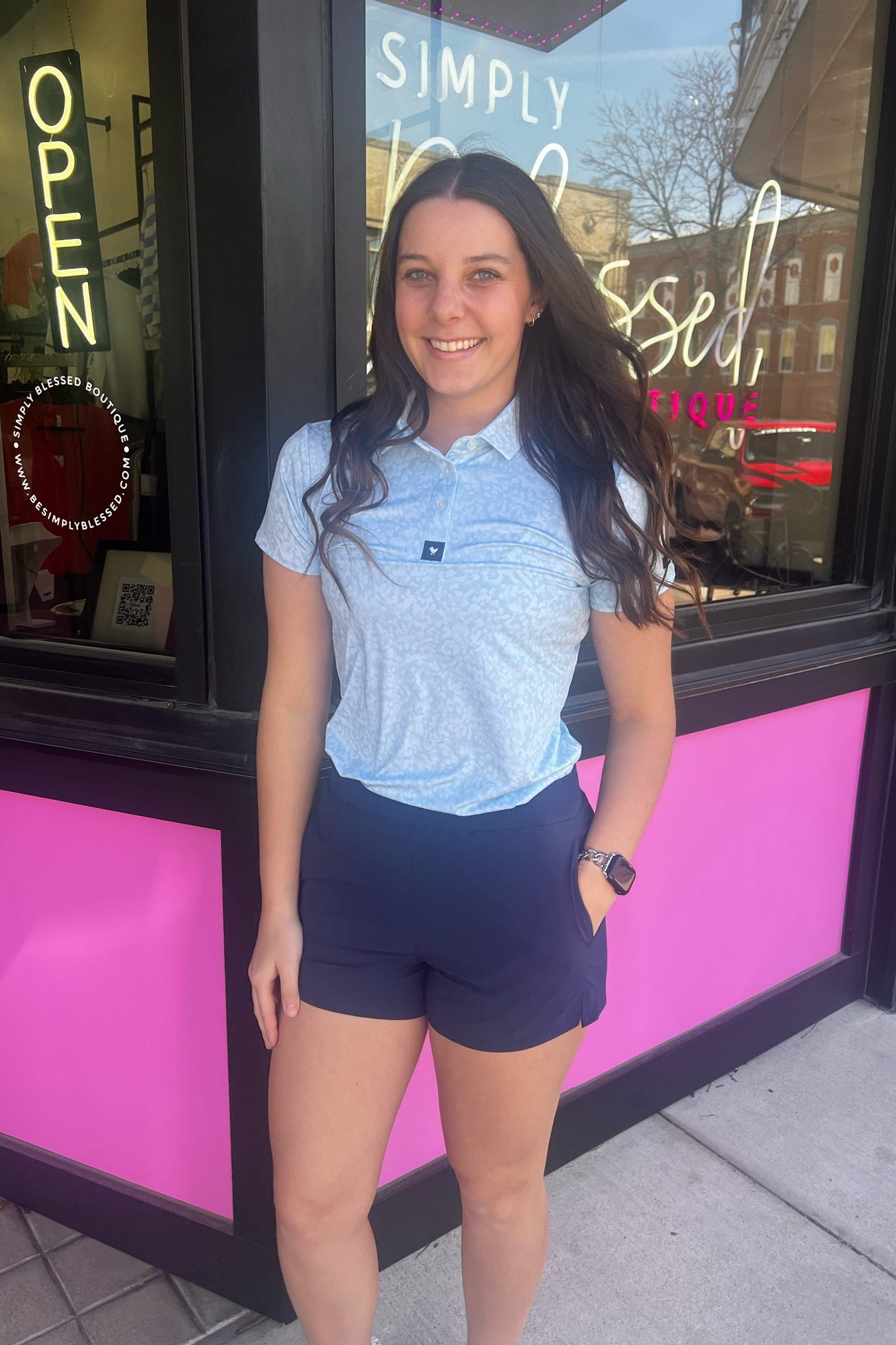 Woman standing in front of a store with a pink and black exterior