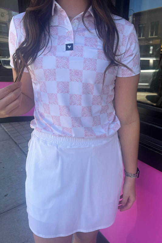 Person wearing a checkered shirt and white skirt on a pink floor.