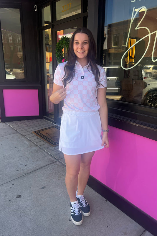 Woman in a white outfit standing in front of a pink building