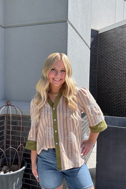 Woman standing outdoors wearing a striped shirt and denim shorts.