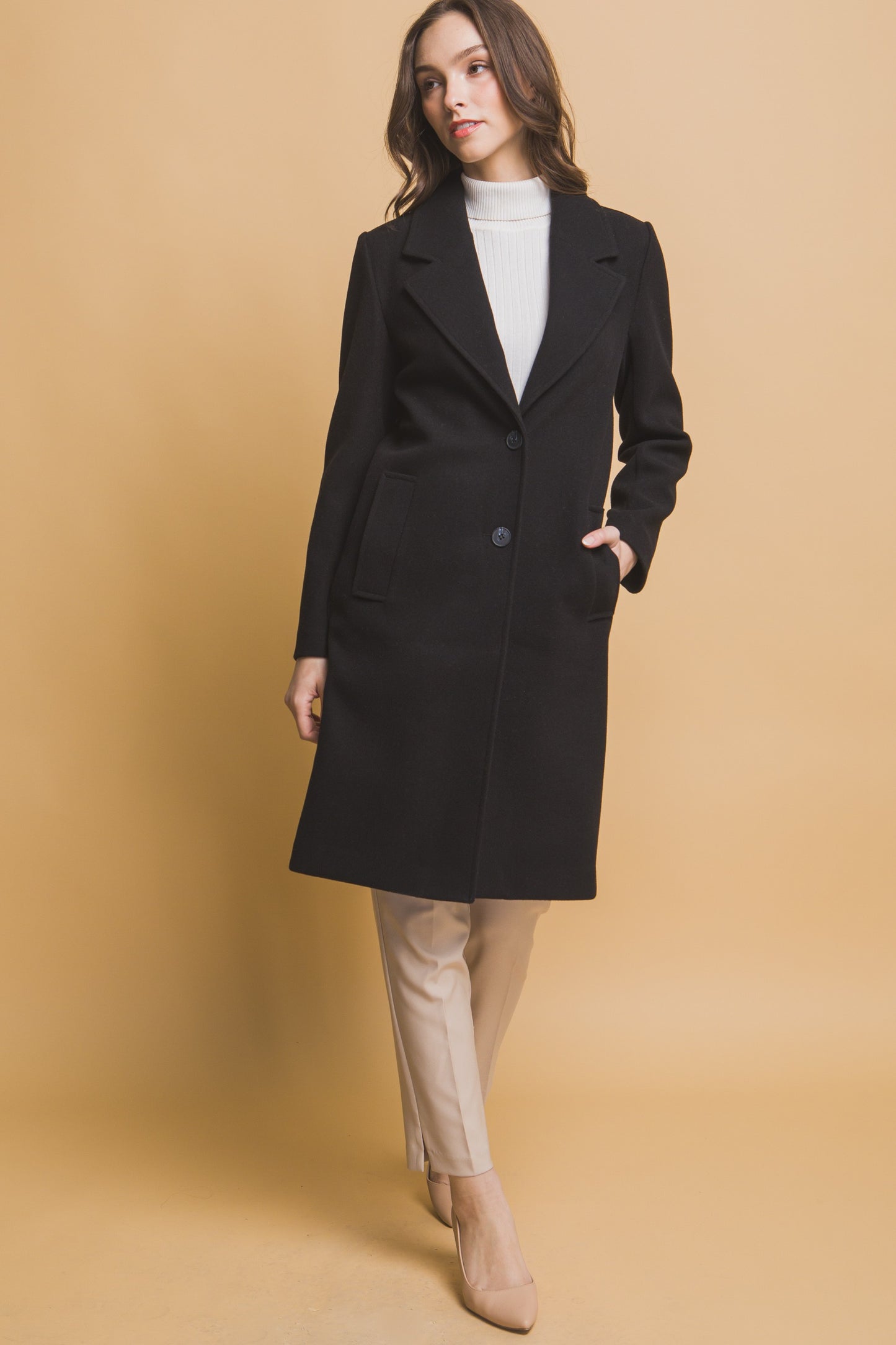 Woman wearing a black coat on a beige background