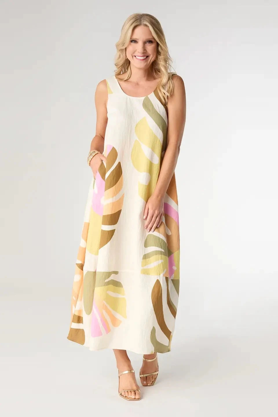 Woman wearing a sleeveless dress with a colorful leaf pattern on a white background