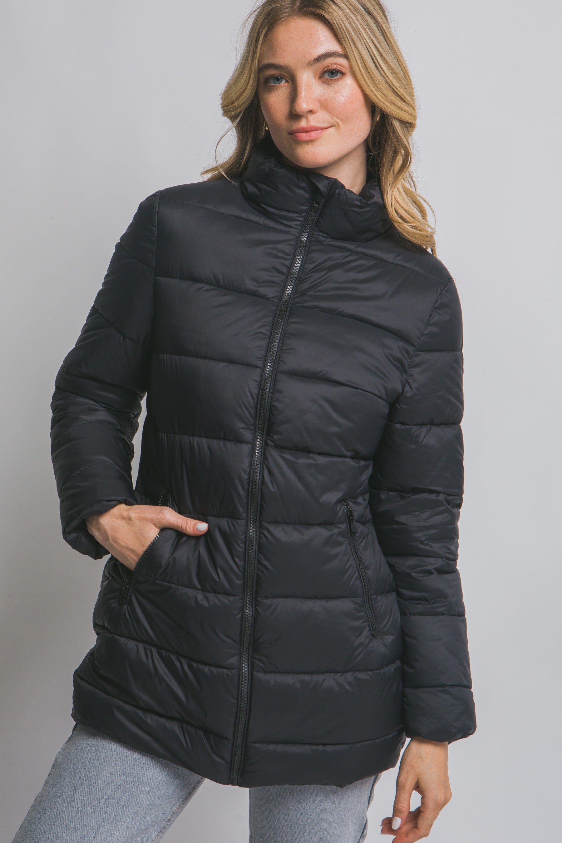 Woman wearing a black puffer jacket against a plain background