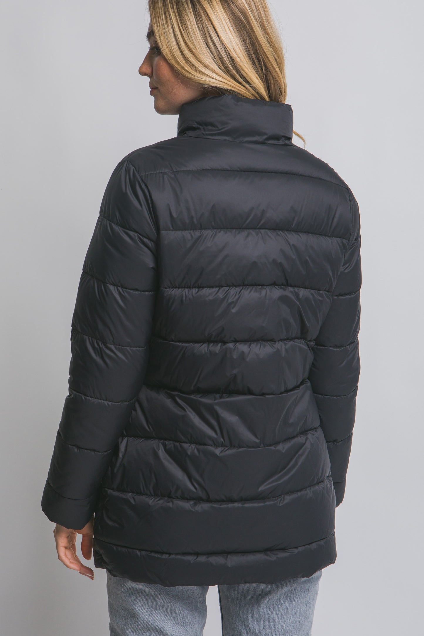 Person wearing a black puffer jacket on a gray background