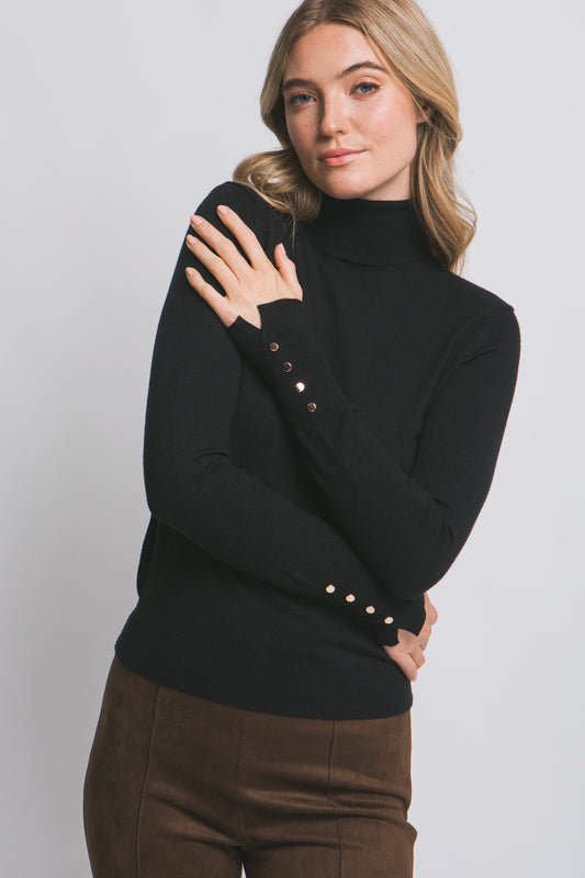Woman wearing a black turtleneck sweater with pearl buttons on a white background