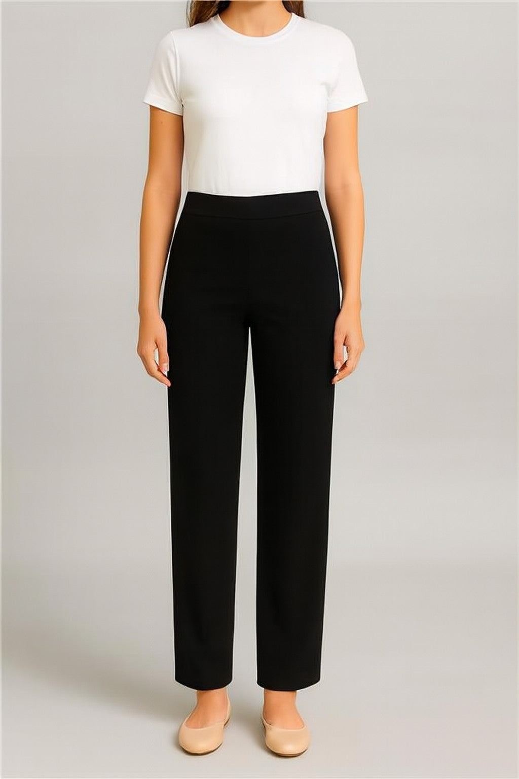 Person wearing a white top and black pants on a plain background