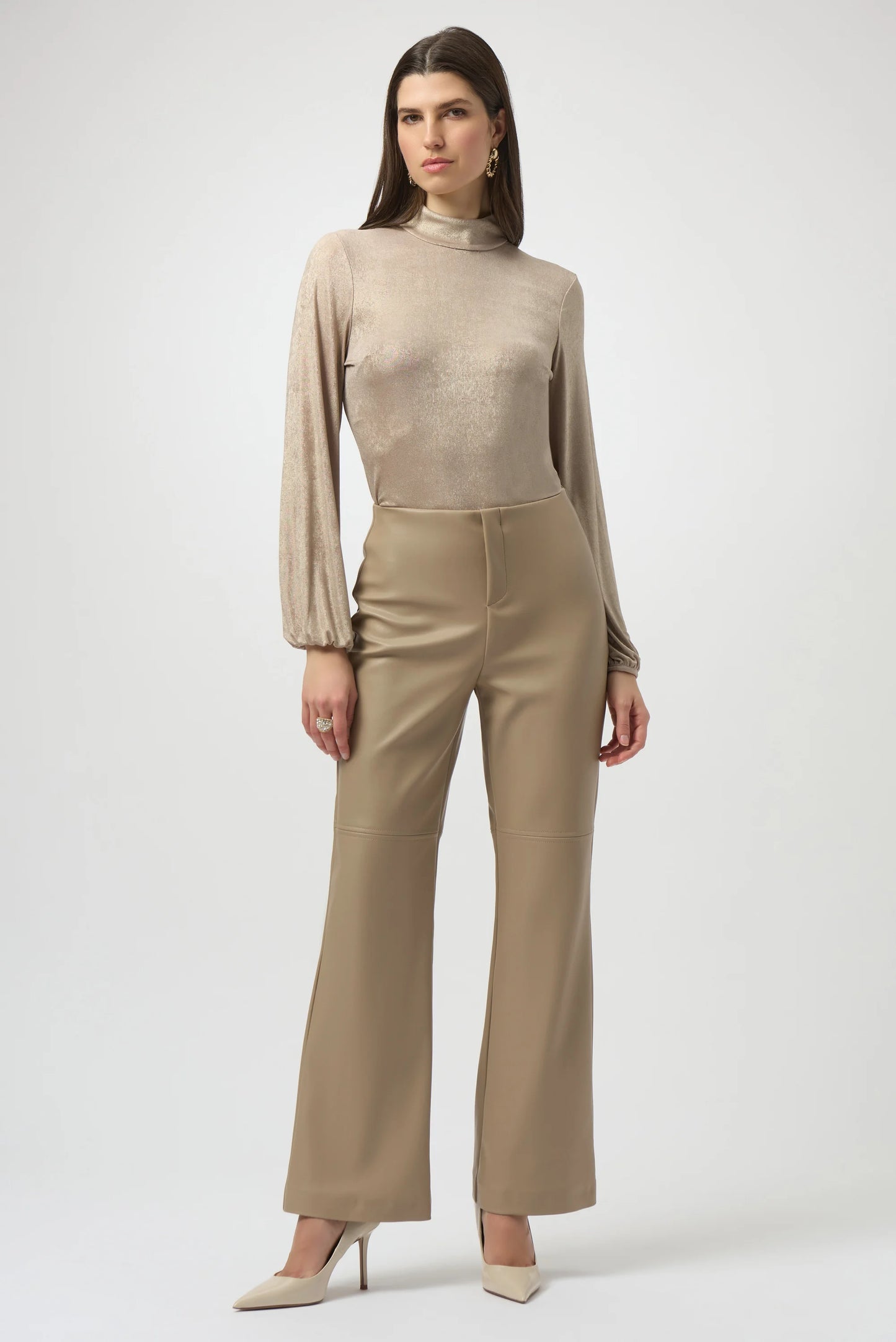 Woman wearing a beige long-sleeve top and high-waisted pants on a white background