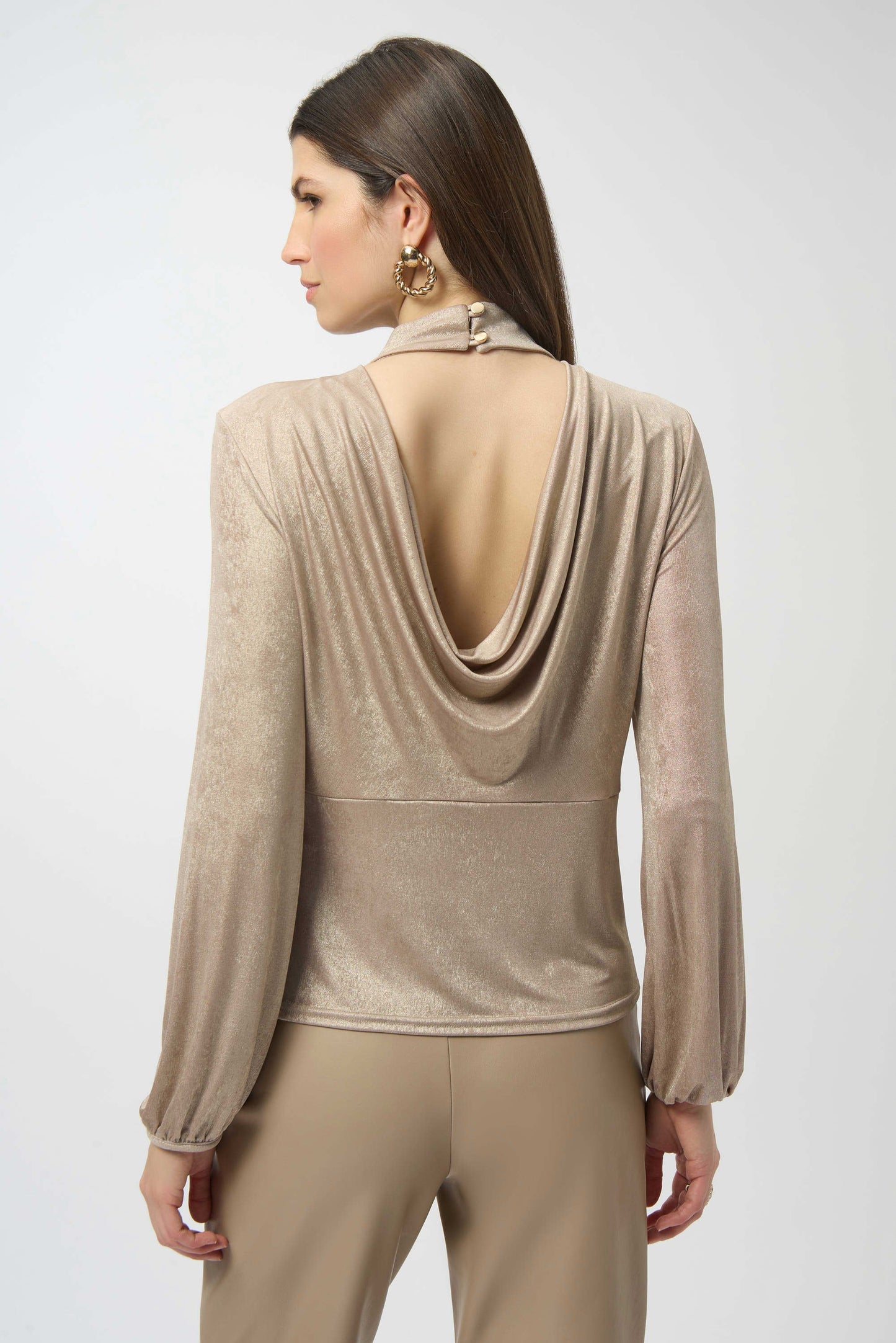 Woman wearing a beige long-sleeve top with a draped back design on a white background
