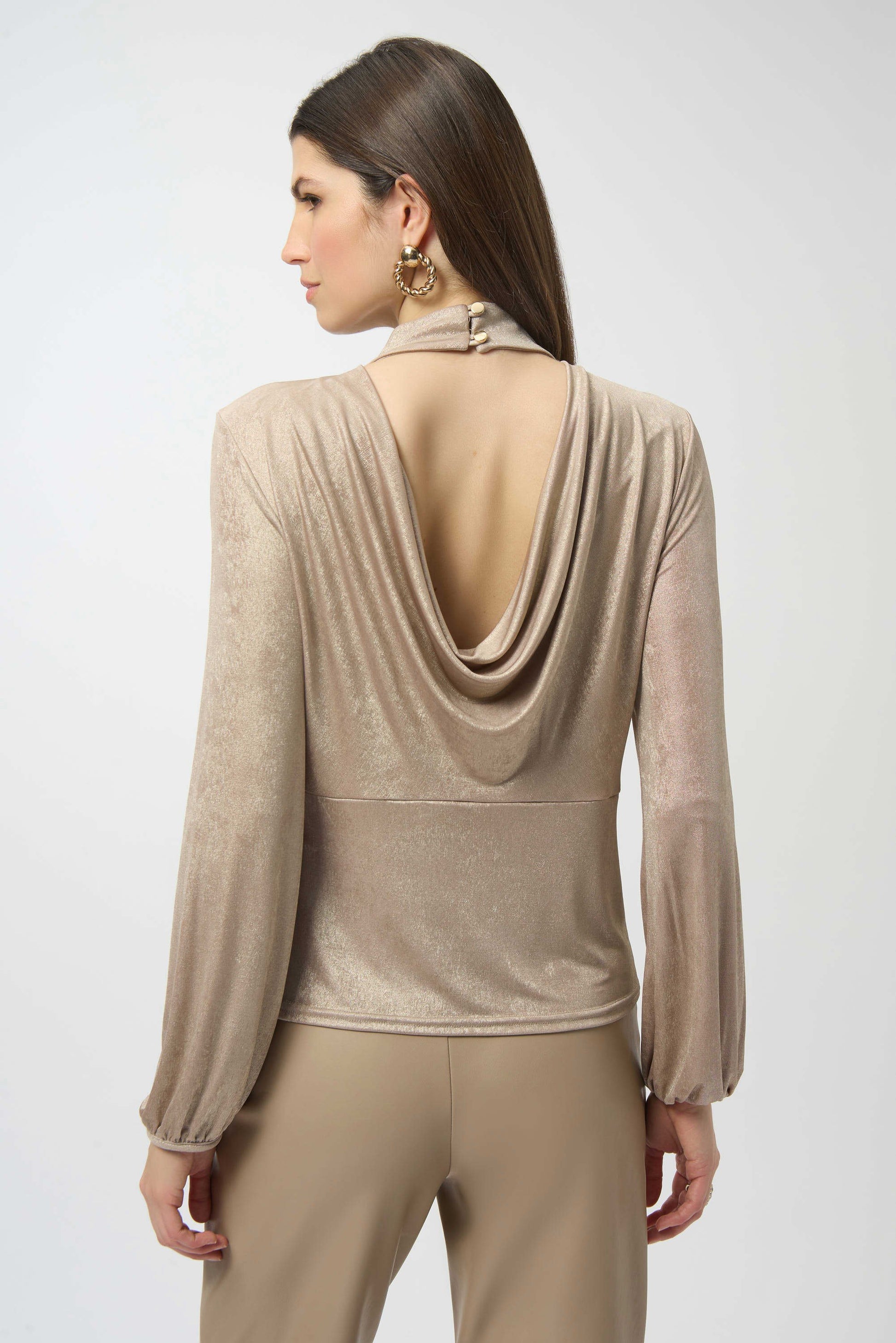 Woman wearing a beige long-sleeve top with a draped back design on a white background