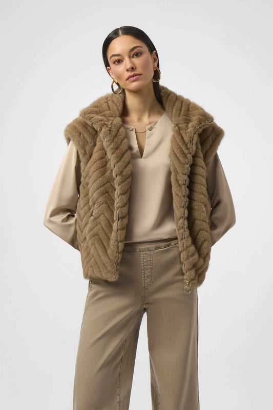 Woman wearing a brown knitted vest over a beige top and pants on a white background
