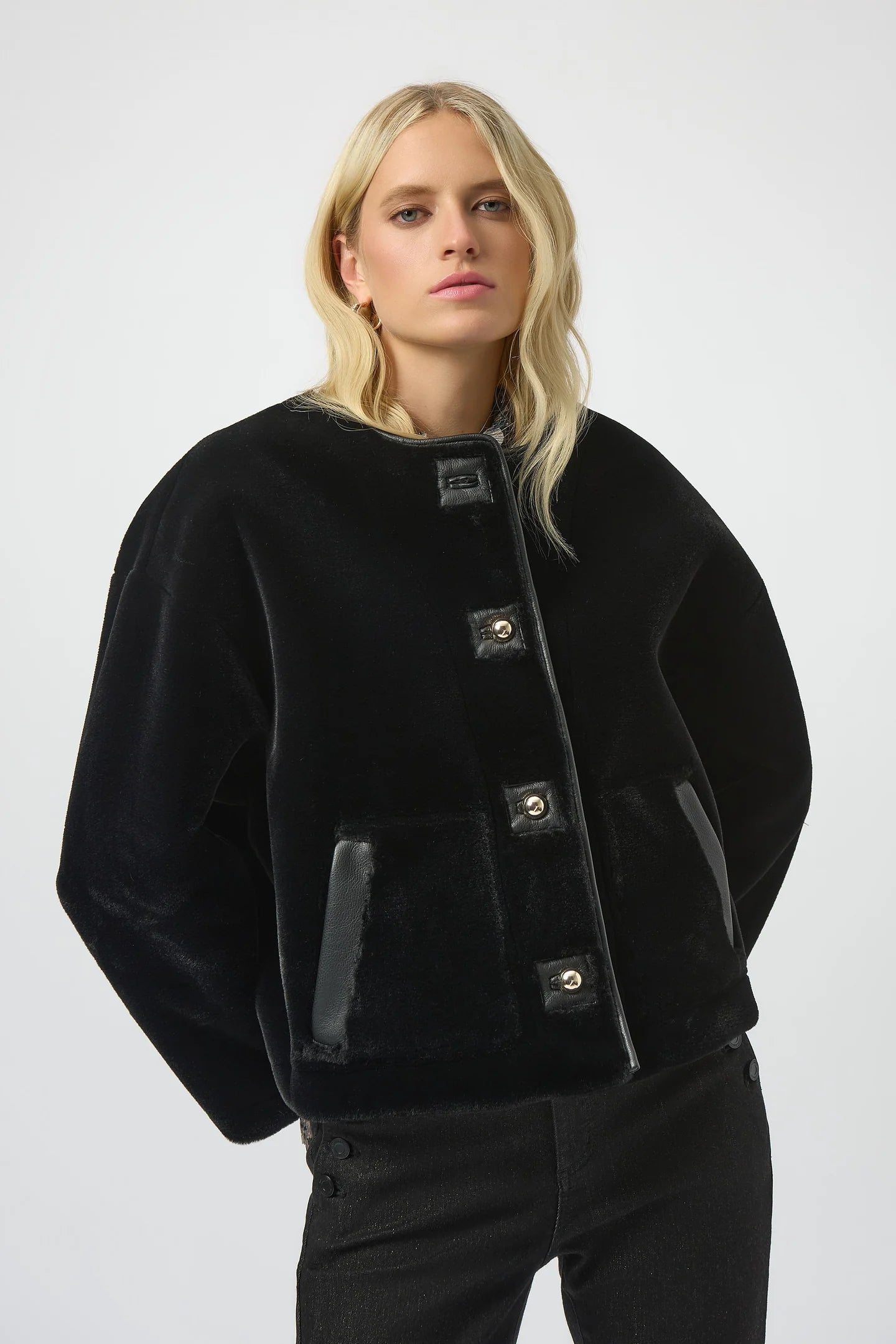 Woman wearing a black jacket with button details on a white background