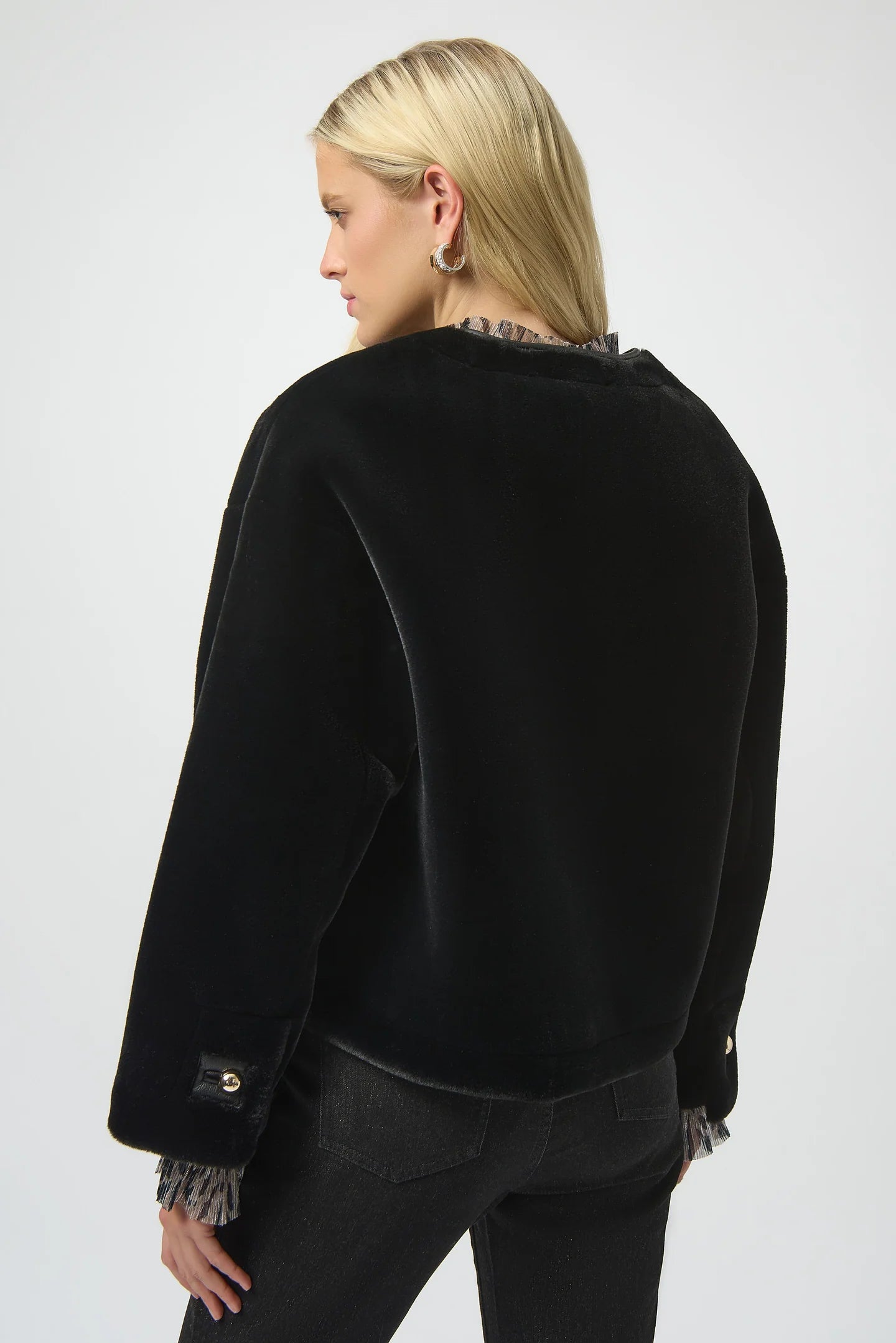 Person wearing a black jacket with frayed cuffs and hem on a white background