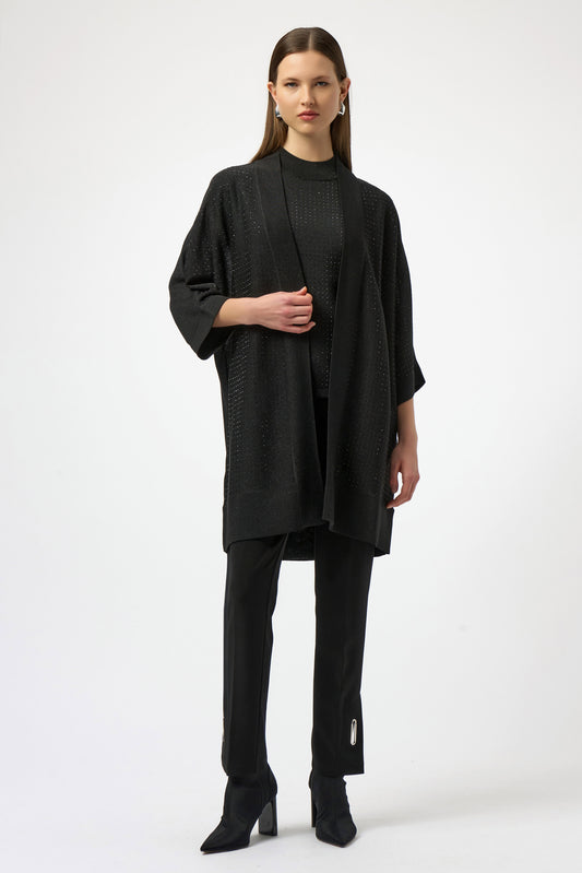 Woman wearing a black outfit with a long cardigan on a white background