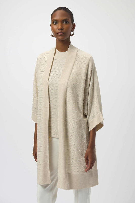 Woman wearing a beige kimono-style garment over a white top and pants on a white background