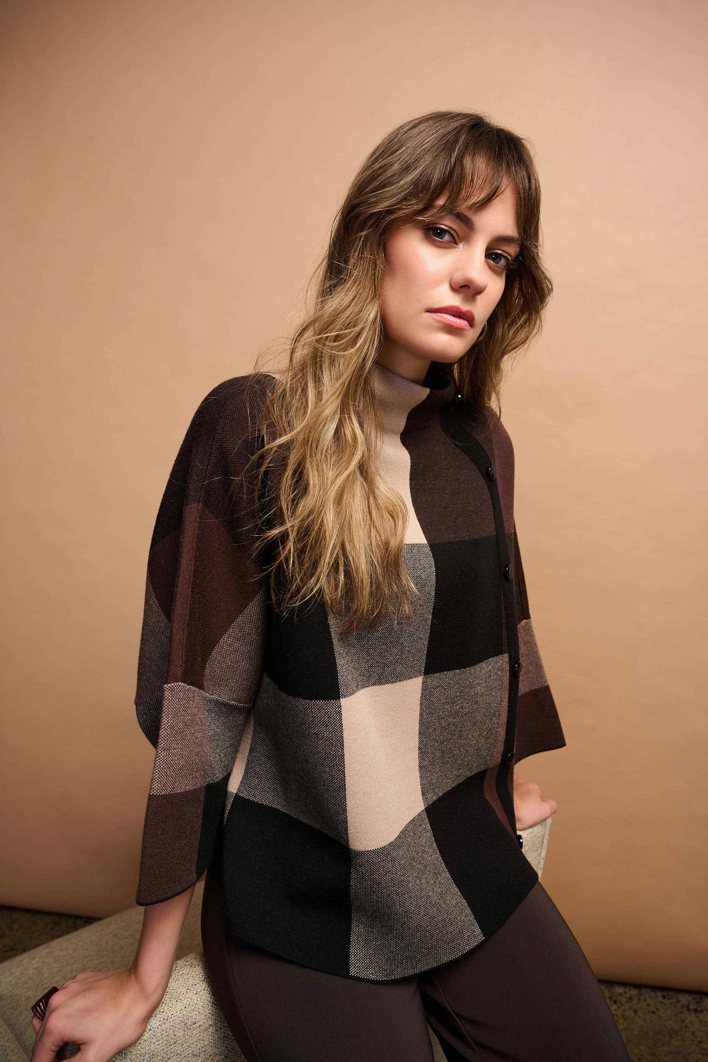 Woman wearing a checkered sweater against a beige background